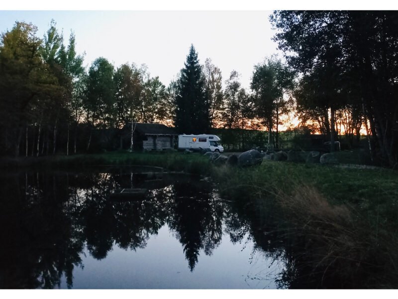 camping-car garé au bord d'un lac avec des sapins à la tombée du jour. Vosges, France