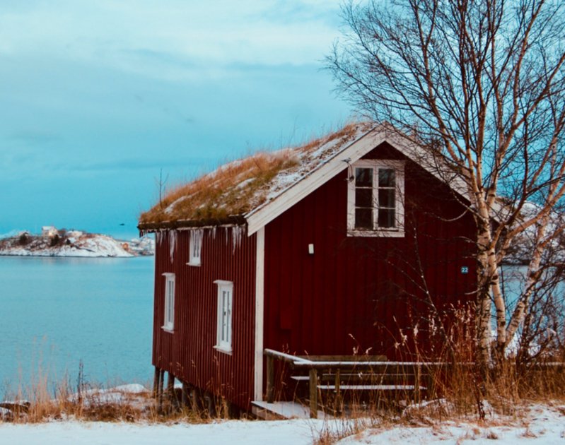 cabane rouge en bois devant la mer sur un sol enneigé en Norège, lofoten