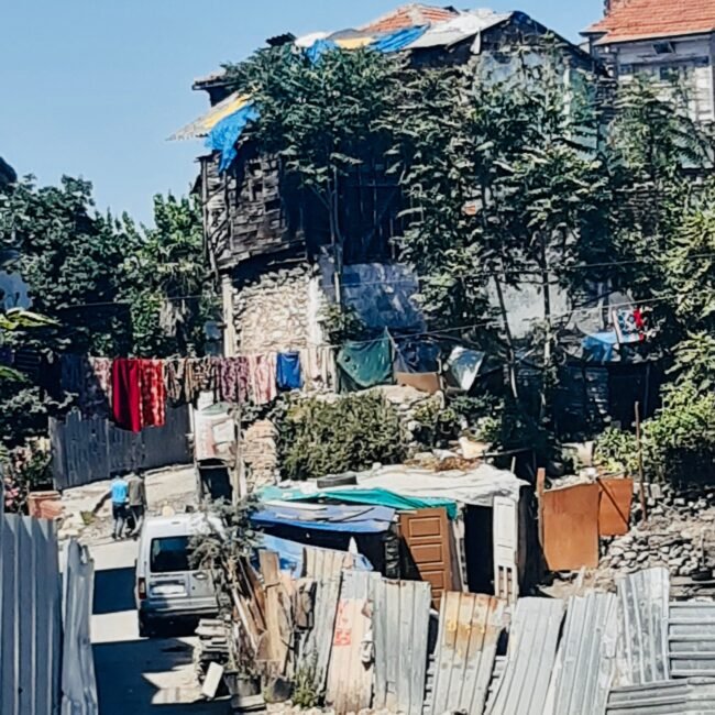 Rue d'un quartier populaire d'Istanbul, avec des barrières en toles et du linge sêchant entre les maisons