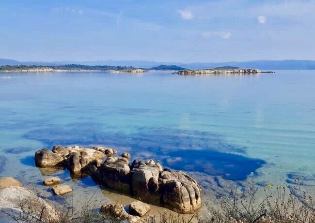 mer bleue azur avec quelques rocher au premier plan