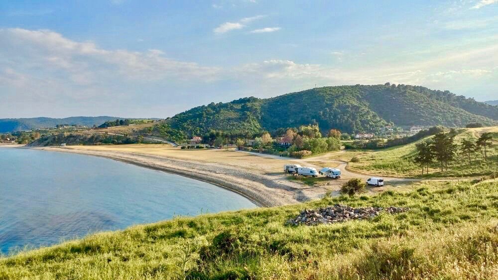 vue sur une longue plage de sable avec 3 campings cars garés à l'extremité